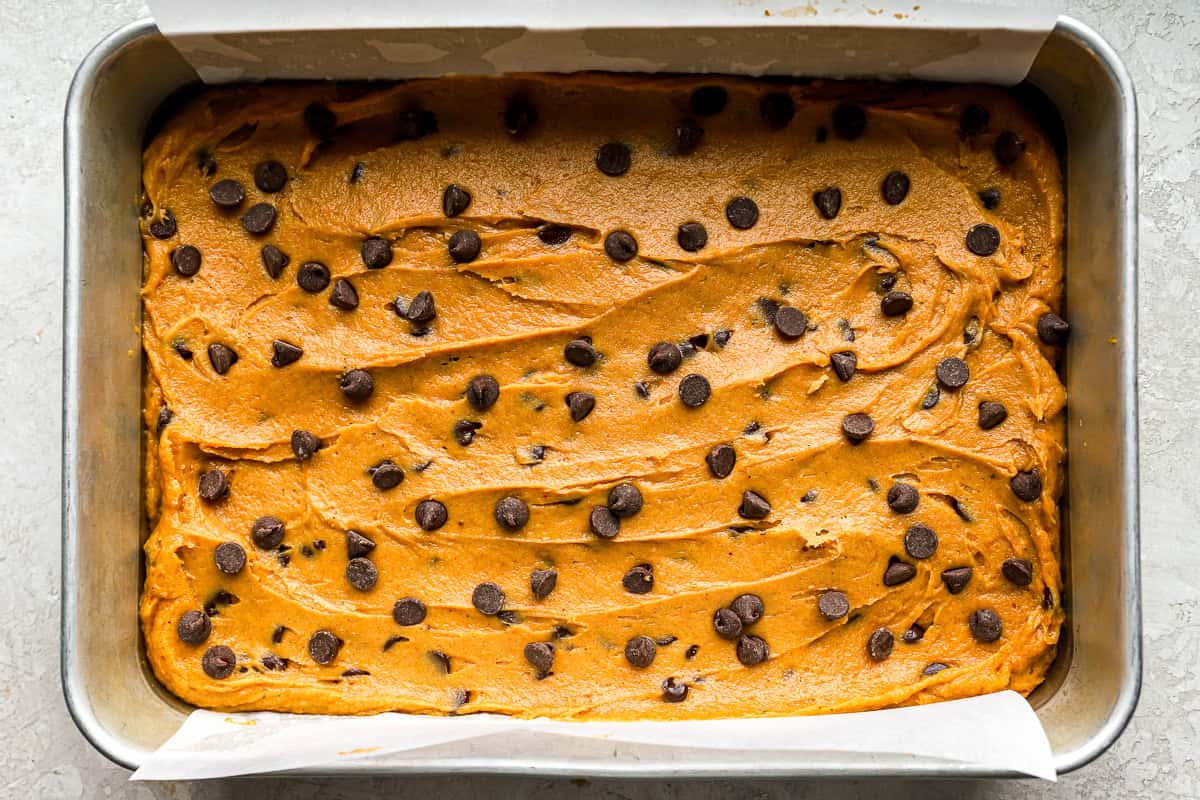 pumpkin cookie bar batter spread in a baking pan.