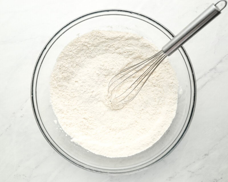 flour in a glass bowl with a whisk.