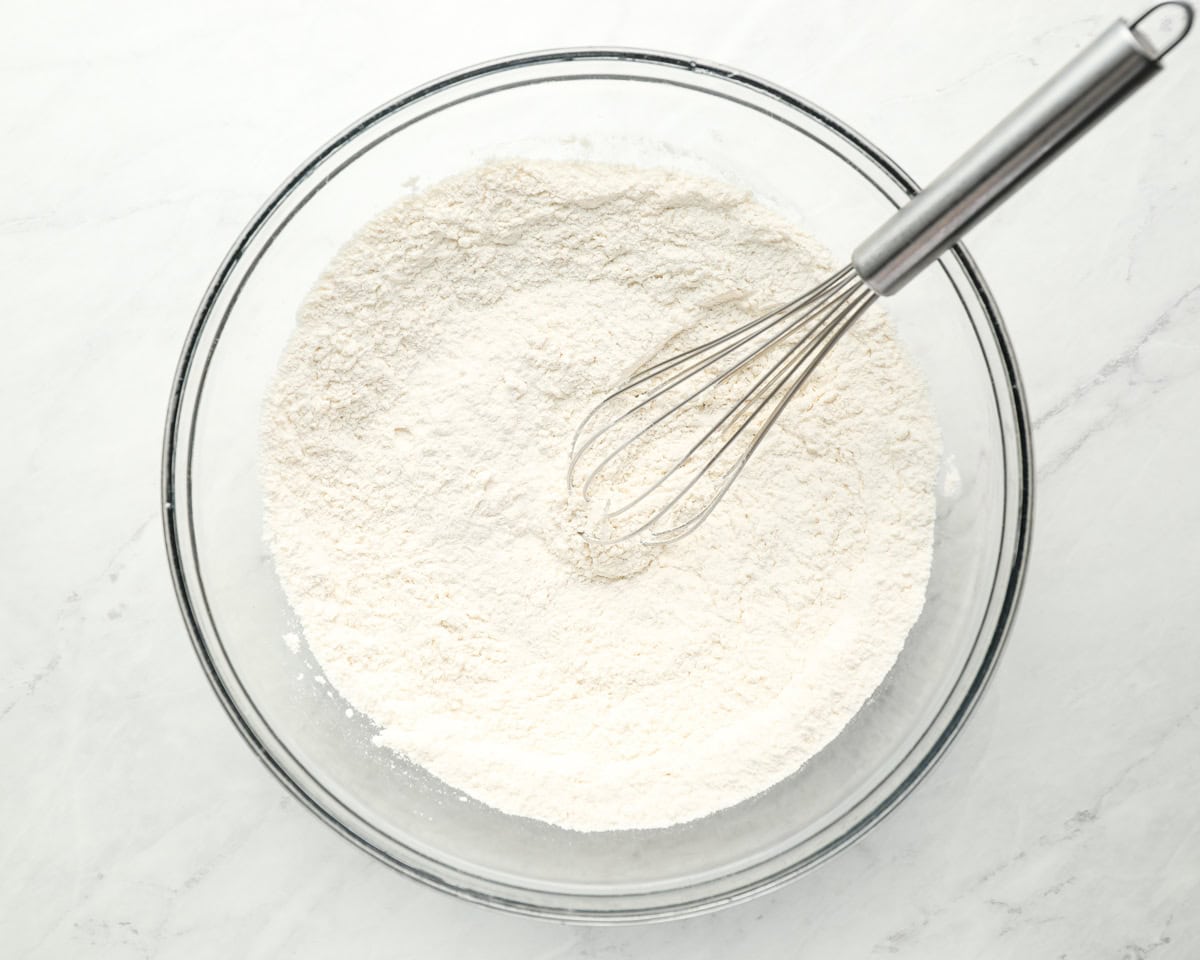 flour in a glass bowl with a whisk.