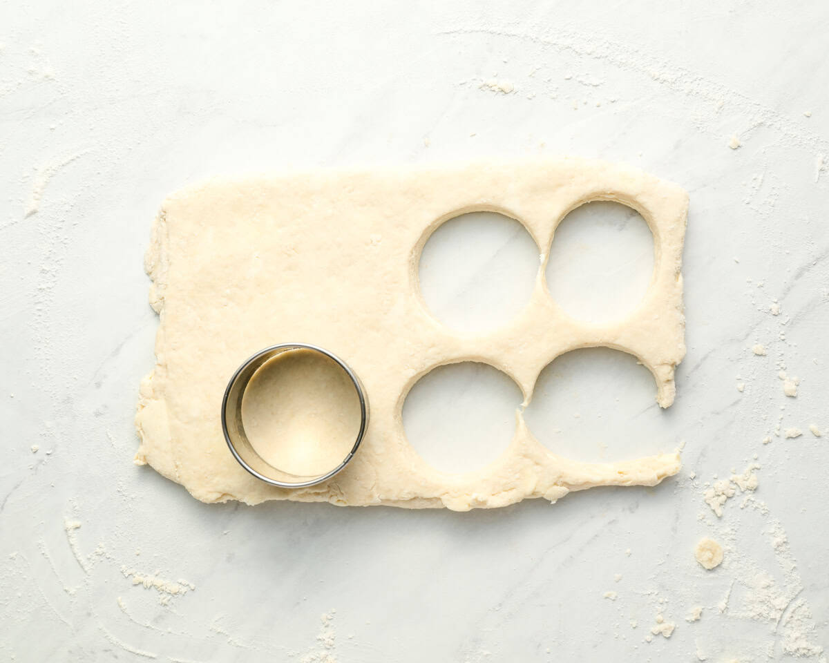 cutting circles out of biscuit dough with a biscuit cutter.