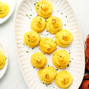 overhead view of duchess potatoes on a white oval serving tray.