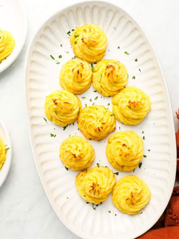 overhead view of duchess potatoes on a white oval serving tray.