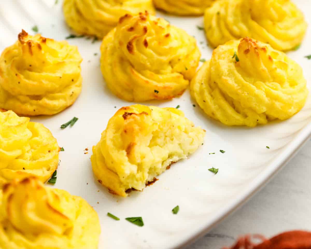 closeup of a halved duchess potato mound on a white tray.