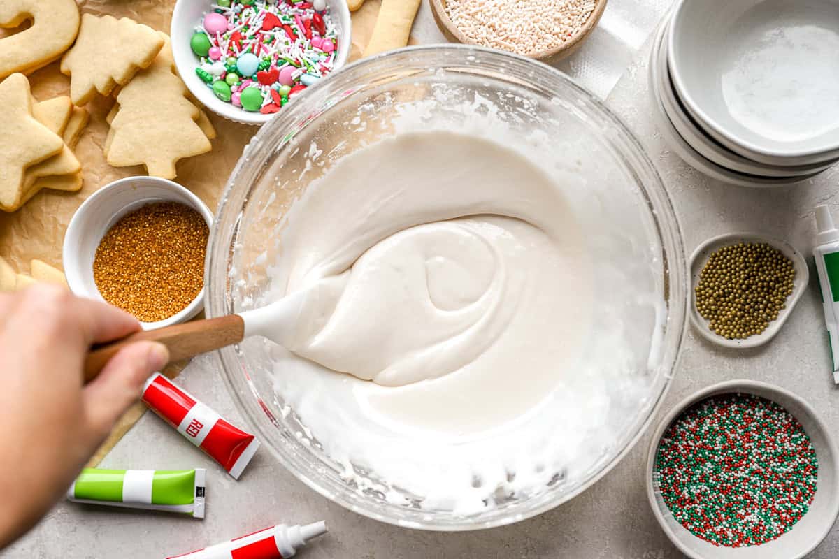 creamy white frosting in a glass bowl with a rubber spatula.