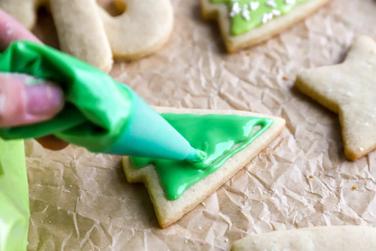 closeup of icing a cutout christmas cookie.