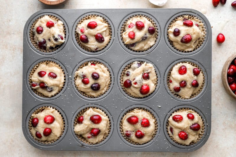 cranberry muffin batter in a muffin tin.