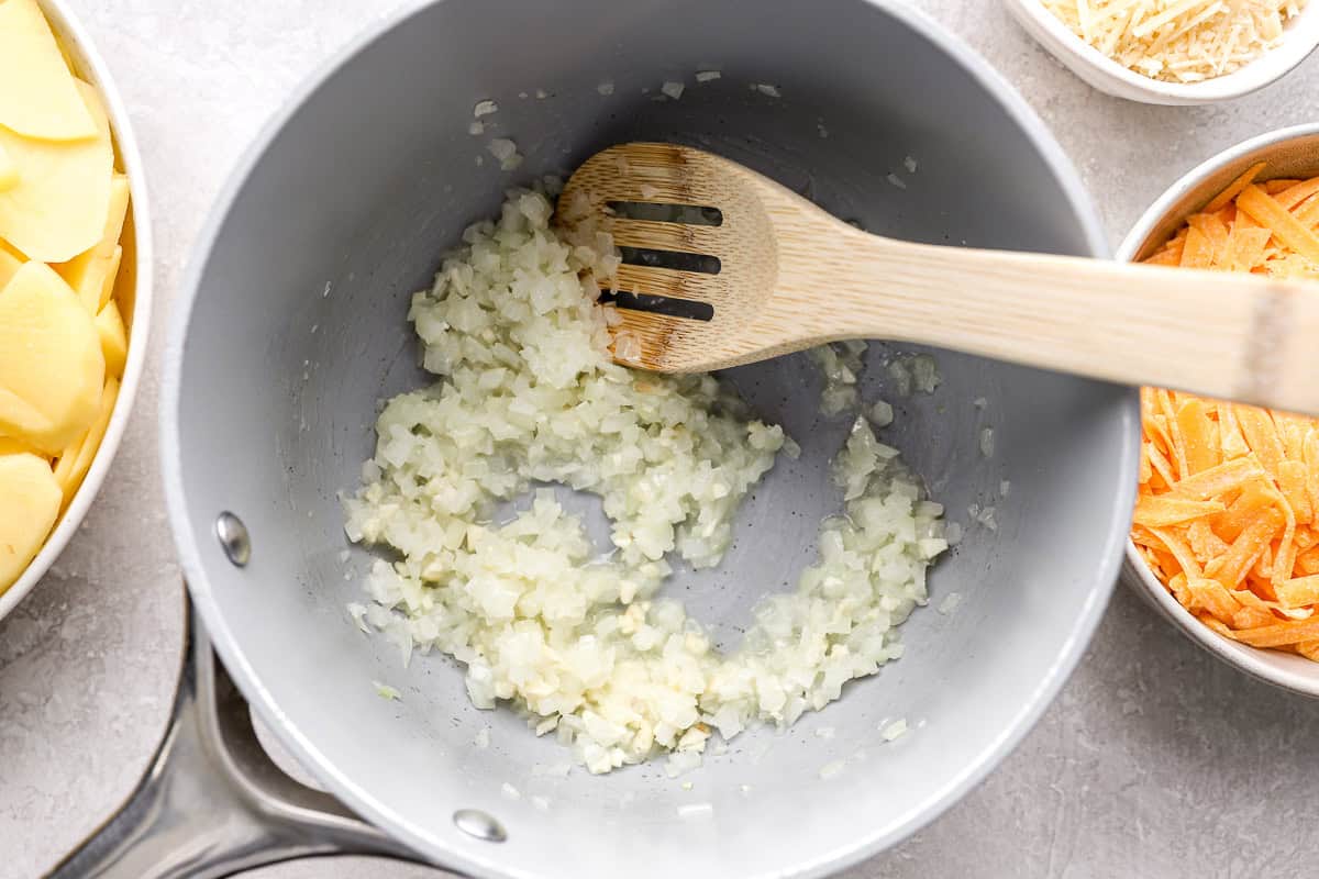 sautéeing onions in a pan with a wooden spoon.