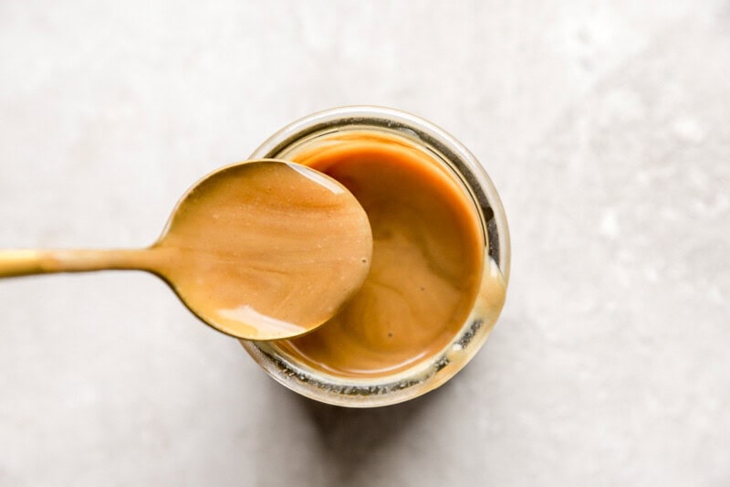 Spoon dipping into a jar of honey dijon.