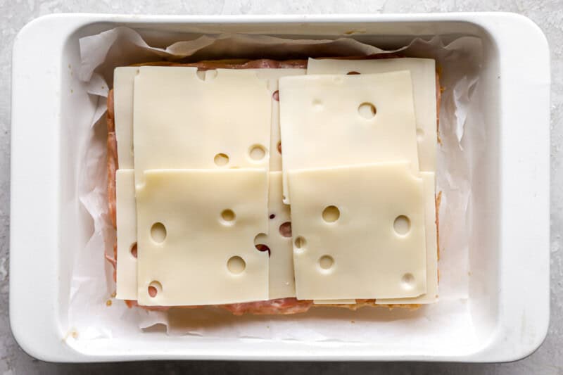 Slices of Swiss cheese piled on top of ham.