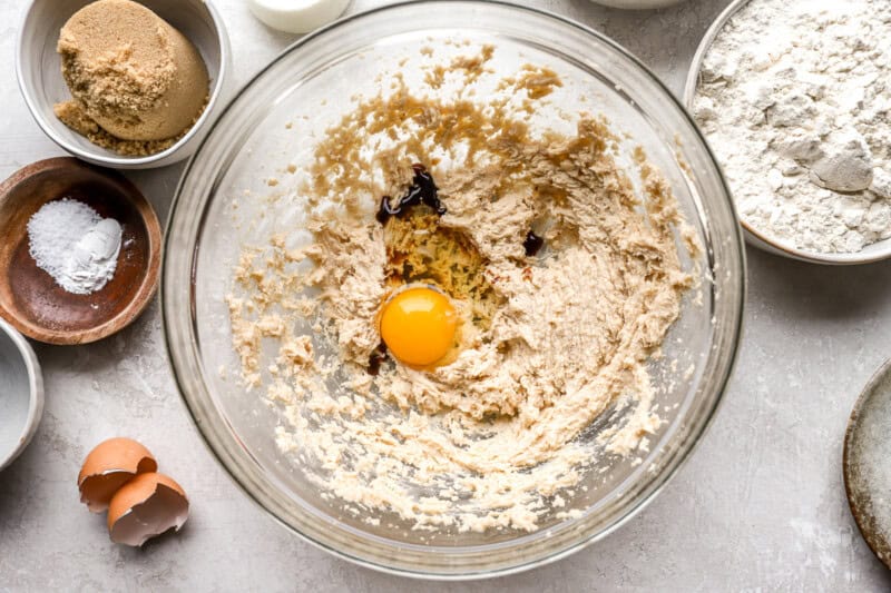 cooke dough with an egg and vanilla added in a glass bowl.