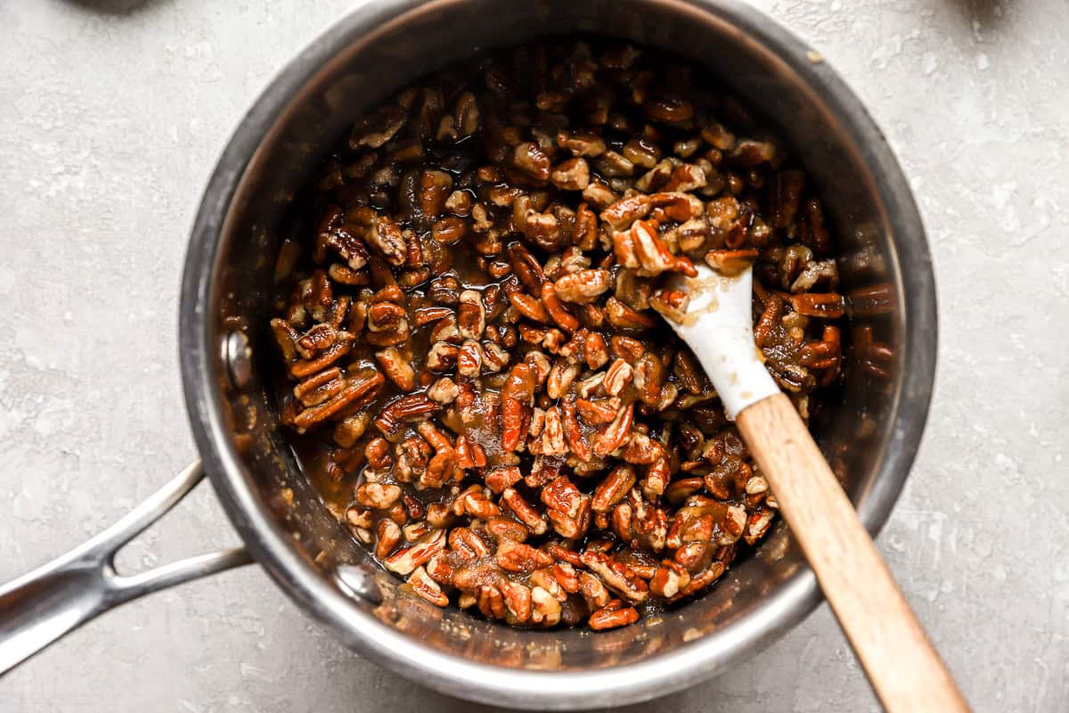 chopped pecans in a saucepan with a rubber spatula.