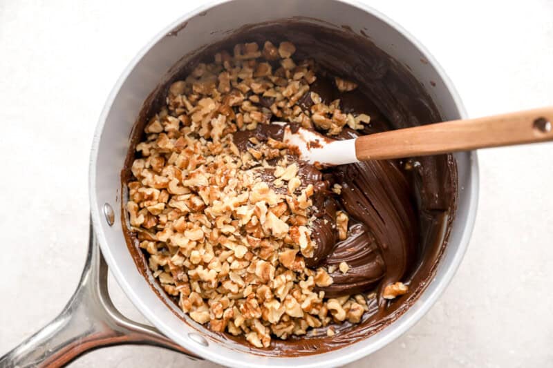 stirring nuts into fudge in a pan with a rubber spatula.