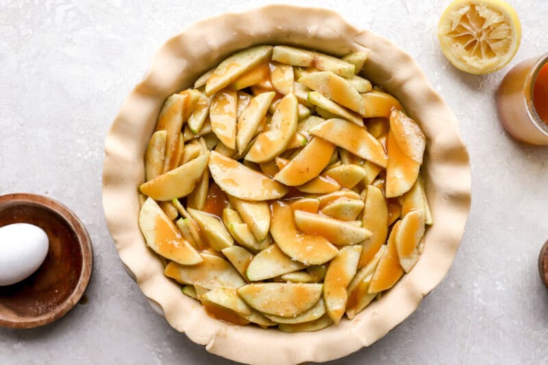 caramel sauce poured over apples in a pie crust.