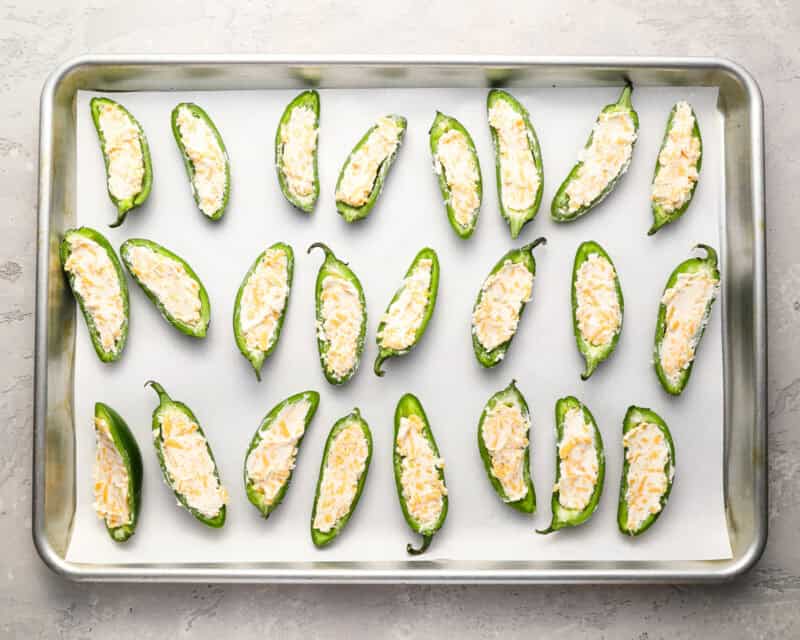 stuffed jalapeno pepper halves on a baking sheet.