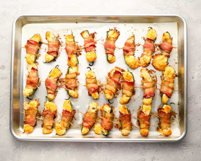 bacon wrapped jalapeno poppers on a baking sheet.