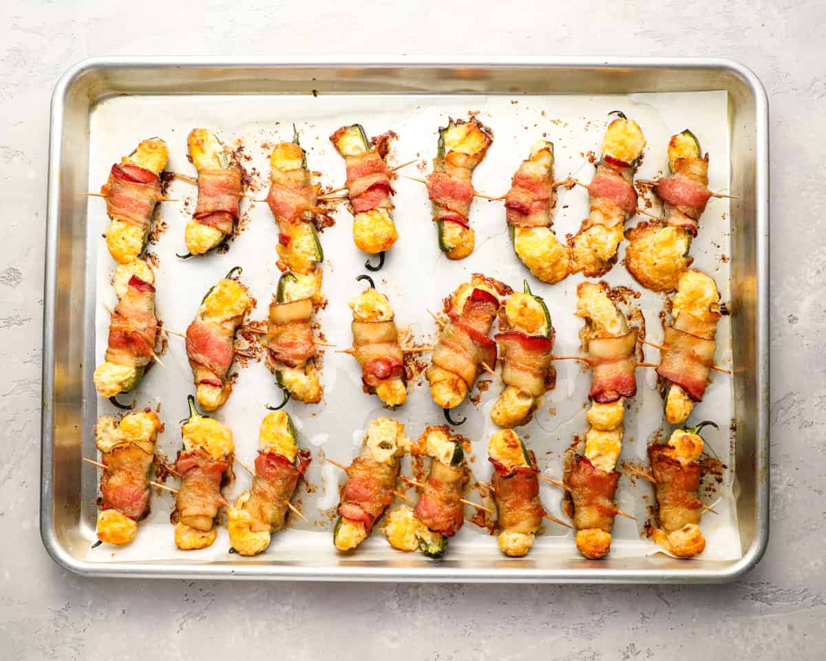 bacon wrapped jalapeno poppers on a baking sheet.