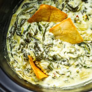 closeup overhead view of spinach artichoke dip in a crockpot with pita chips.