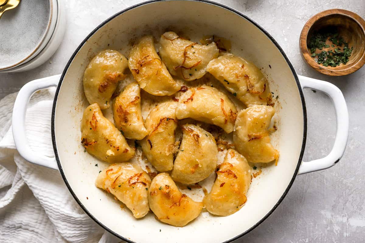 pierogi tossed in butter sauce in a pot.