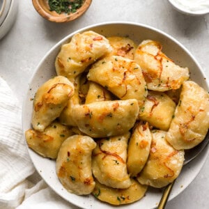 homemade pierogies on a white plate with a spoon.