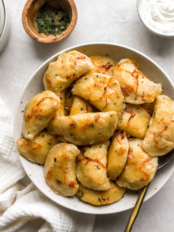 homemade pierogies on a white plate with a spoon.