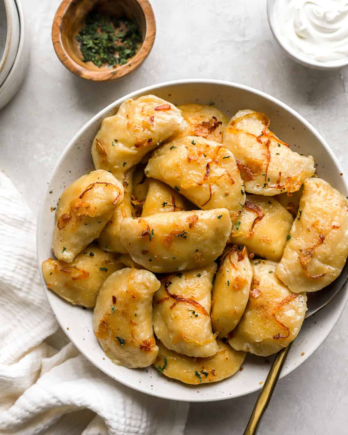 homemade pierogies on a white plate with a spoon.