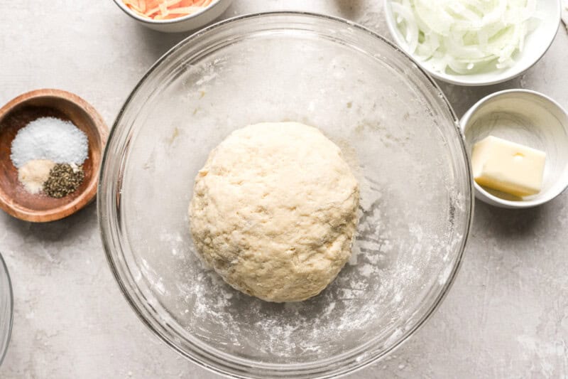 a ball of dough in a bowl with a whisk.