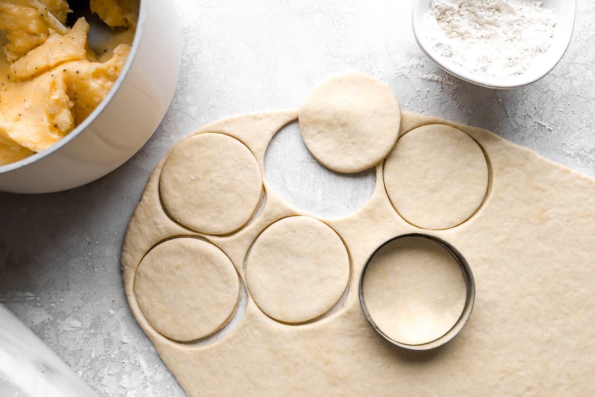 cutting circles out of dough with a cookie cutter.