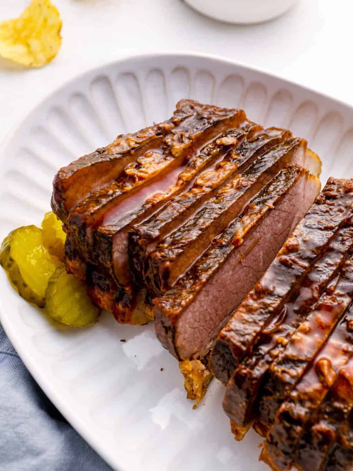 Sliced slow cooker brisket on a white serving plate.